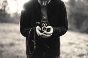 Man standing in a field focuses a camera